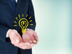 ビジネスマンの手とひらめき電球・提案・解決策イメージ