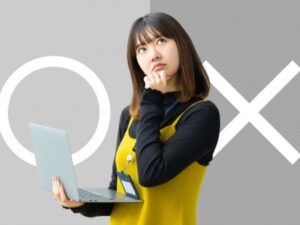 OX背景でパソコンを持ち考える女性